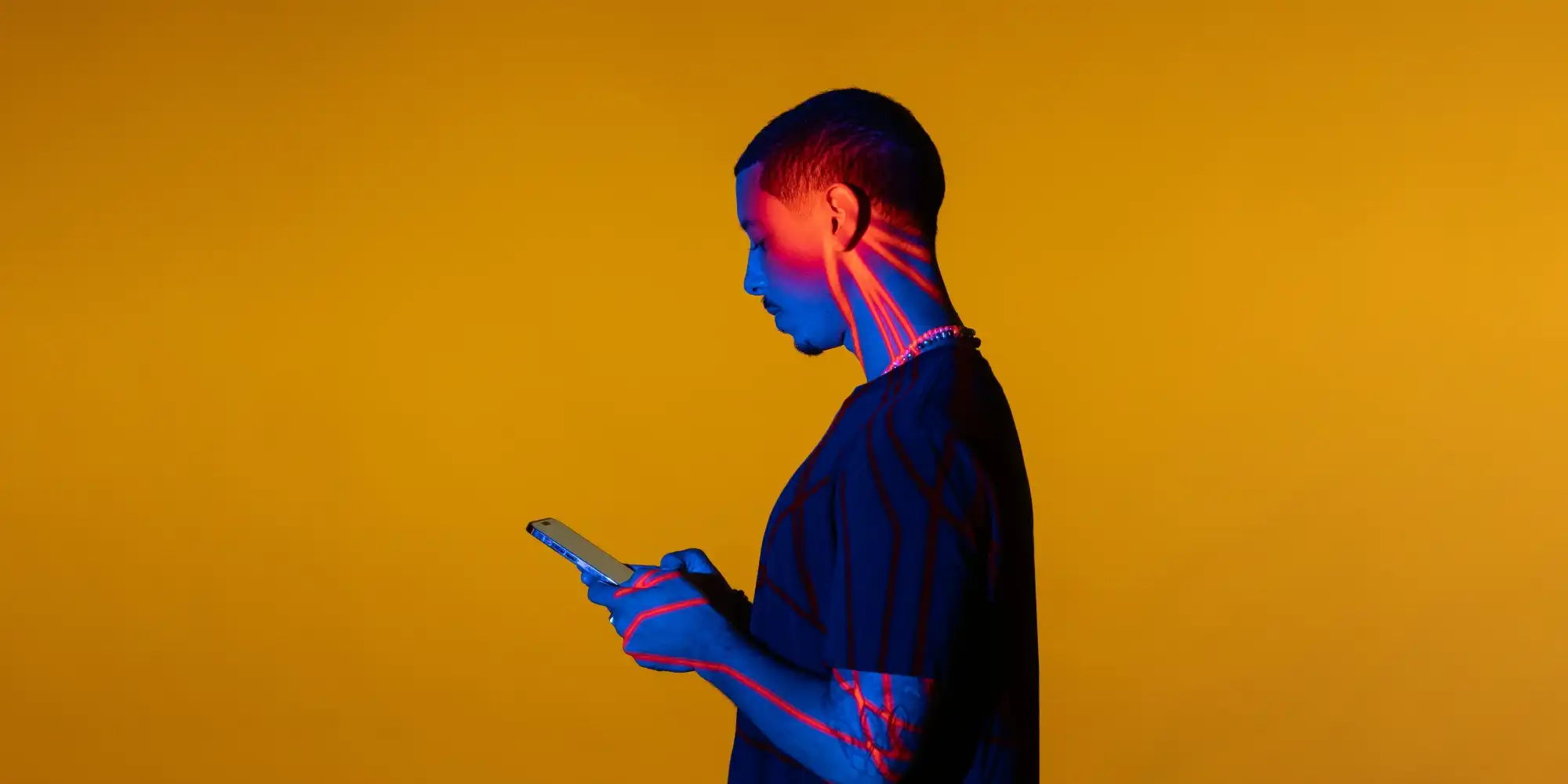 a young man on his phone is lit up by the energy of social media interaction